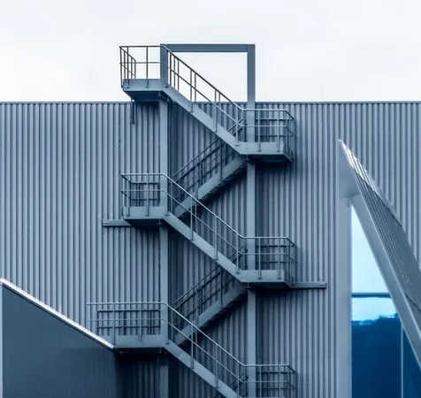 Scară metalică exterioară de evacuare pe fațada unei clădiri industriale
