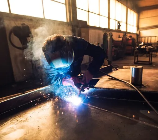 Sudor cu mască de protecție care sudează o piesă metalică în atelier
